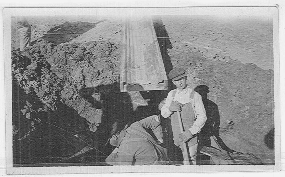 Unidentified workers excavating to set forms for a foundation.