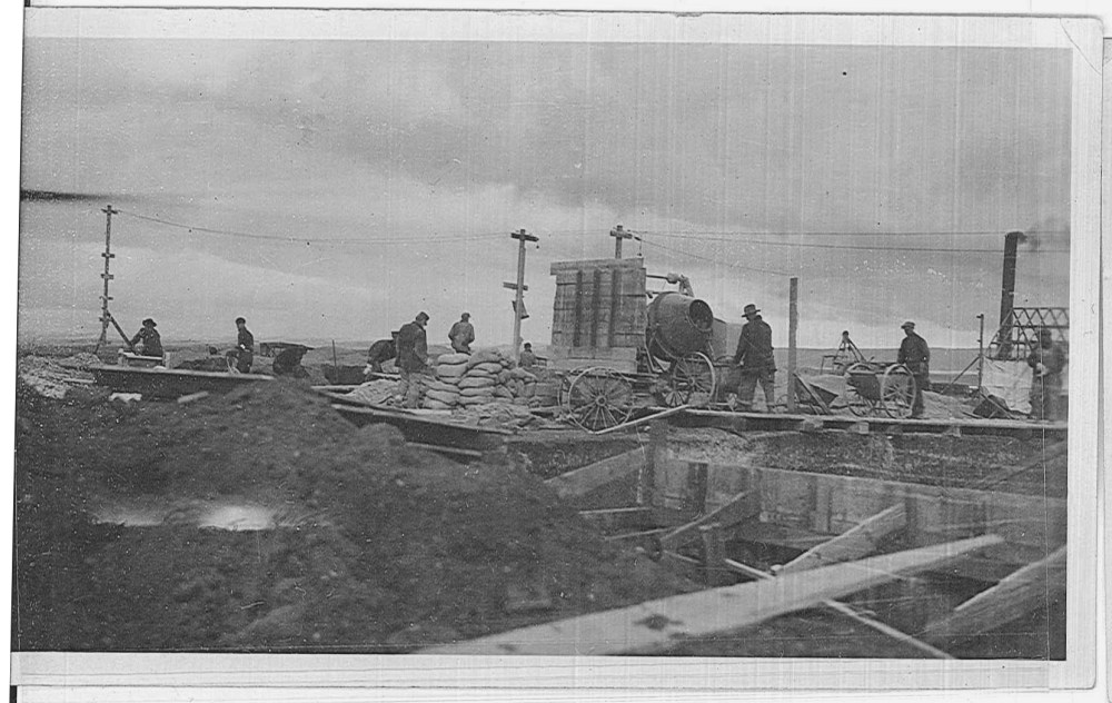 Cement is prepared in a portable mixer. A concrete form is seen in the foreground. 