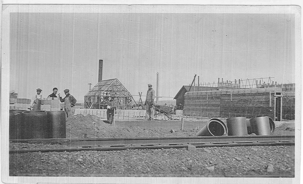 The buildings in the background were temporary construction buildings, similar to modern-day construction trailers. Note the wooden forms that are to the right side of the image.