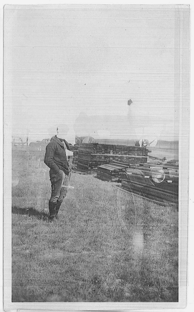 As was common with early photographs that were made with glass plates, one image is superimposed over another. The lumber in this image was probably used as concrete forms.